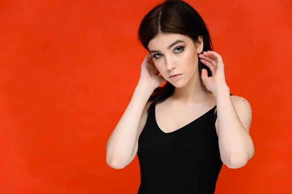 Retrato de close-up de uma jovem estudante bonita com cabelo preto longo, em um fundo vermelho. Ele fica bem na frente da câmera, mostrando suas mãos em poses diferentes com emoções diferentes. . — Fotografia de Stock