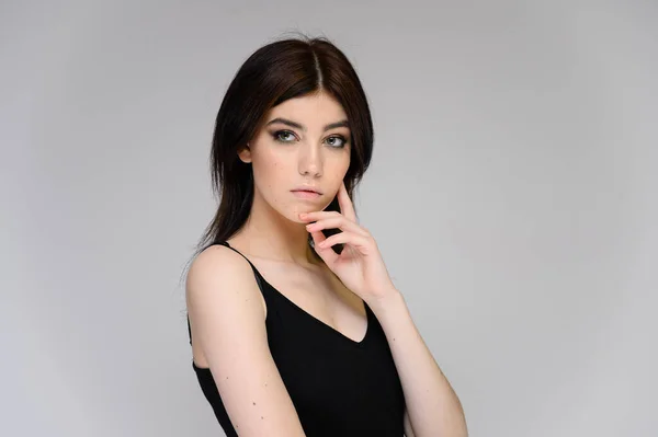 Retrato de cerca de una joven estudiante con el pelo largo y negro, sobre un fondo blanco. Se para justo delante de la cámara, mostrando sus manos en diferentes poses con diferentes emociones . — Foto de Stock