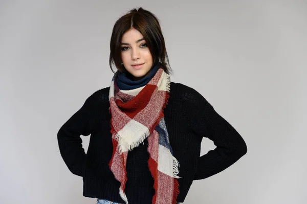 Close-up portrait of a young pretty girl student with long black hair with a scarf and in a sweater, on a white background. Standing right in front of the camera in different poses with emotions. — Stock Photo, Image