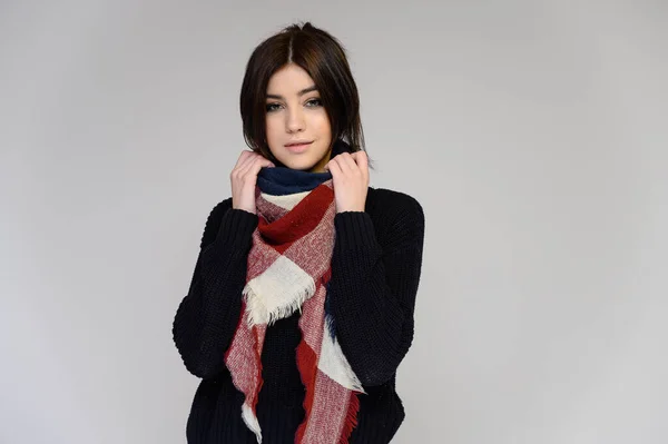 Close-up portrait of a young pretty girl student with long black hair with a scarf and in a sweater, on a white background. Standing right in front of the camera in different poses with emotions. — Stock Photo, Image