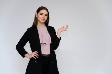 Beyaz bir arka planda, siyah takım elbiseli, uzun siyah saçlı, güzel bir sekreterin yakın plan portresi. Farklı pozlarda kameranın önünde durarak..