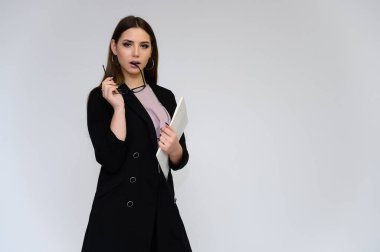 Beyaz bir arka planda, siyah takım elbiseli, uzun siyah saçlı, güzel bir sekreterin yakın plan portresi. Farklı pozlarda kameranın önünde durarak..