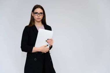 Beyaz bir arka planda, siyah takım elbiseli, uzun siyah saçlı, güzel bir sekreterin yakın plan portresi. Farklı pozlarda kameranın önünde durarak..