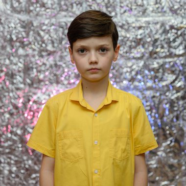 Genç çocuk için tatil fotoğrafı konsepti. Sarı gömlekli parlak bir arka planda bir erkek bebeğin portresi. Farklı pozlarda kameranın önünde duruyor. Duygularıyla..