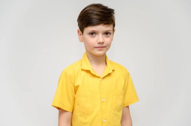 Kavramsal çocuk gösterileri farklı filmlerdeki kahramanların davranışlarını taklit eder. Beyaz arka planda sarı gömlekli bir çocuğun portresi. Kameranın önünde durup, duygularınla poz vermek..