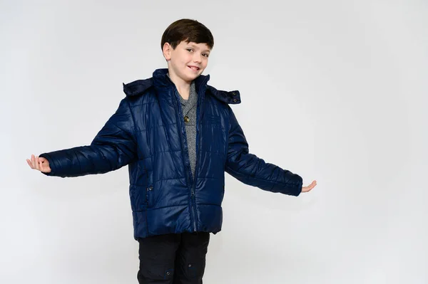 Le concept de vêtements d'hiver et chauds pour un adolescent. Portrait d'un petit garçon sur fond blanc vêtu d'une veste et d'un pantalon d'hiver. Se tient devant la caméra dans différentes poses avec des émotions . — Photo