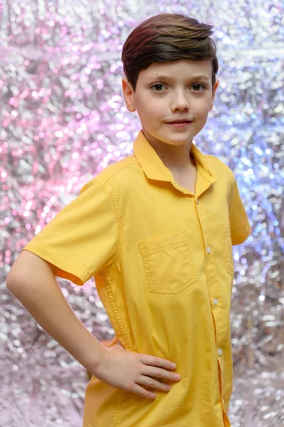 Концепция праздничных фотографий для подростка. Портрет мальчика на блестящем фоне в жёлтой рубашке. Стоят перед камерой в разных позах с эмоциями . — стоковое фото