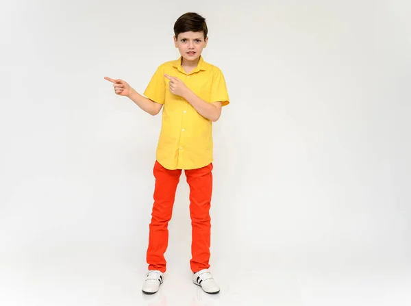 Teenager Schoolboy Boy Concept Shows Emotion. Foto completa de un niño en pantalones rojos y una camisa amarilla sobre un fondo blanco en el estudio. Se coloca delante de la cámara en varias poses . —  Fotos de Stock