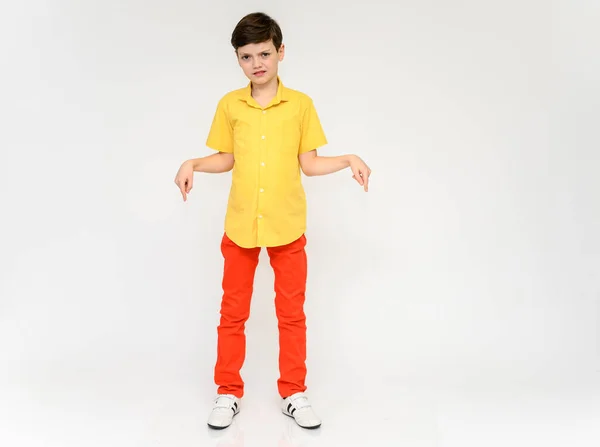 Nastoletni uczeń, koncepcja chłopca, pokazuje emocje. Pełne zdjęcie dziecka w czerwonych spodniach i żółtej koszuli na białym tle w studio. Stoi przed kamerą w różnych pozycjach. — Zdjęcie stockowe