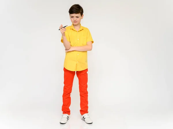 Мальчик-школьник вызывает эмоции. Полная фотография ребенка в красных штанах и желтая рубашка на белом фоне в студии. Стоят перед камерой в различных позах . — стоковое фото
