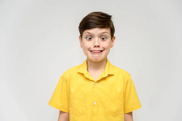 Concetto ragazzo adolescente mostra imita il comportamento di eroi da diversi film. Ritratto di bambino su sfondo bianco con camicia gialla. In piedi davanti alla telecamera in posa con le emozioni . — Foto Stock