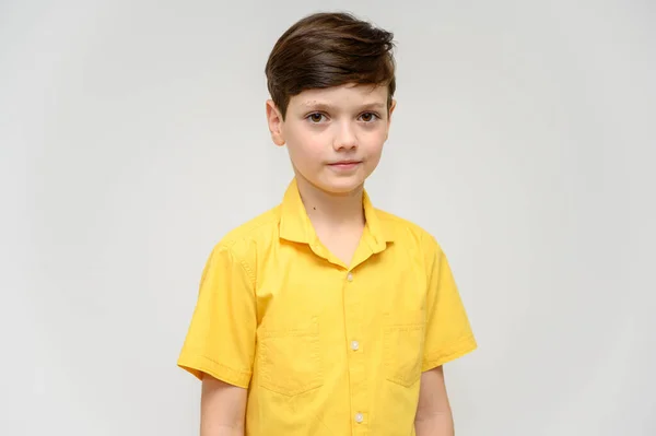 컨셉 보이 십 대 소년은 다른 영화에 나오는 영웅들의 행동을 모방 합니다. 흰색 배경에 노란 셔츠를 입은 아이의 사진. 감정에 휘말린 채 카메라 앞에 서 있는 모습. — 스톡 사진
