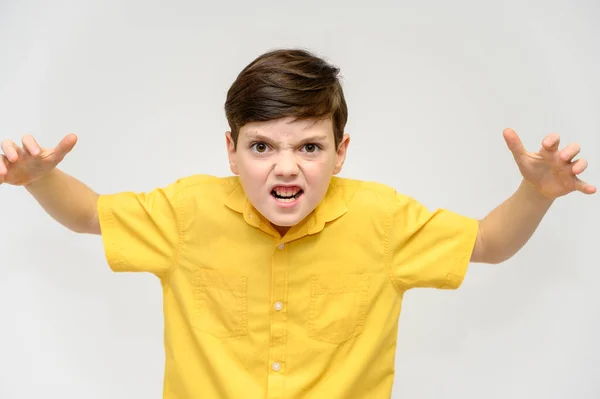 Concept boy teenager shows imitates the behavior of heroes from different movies. Portrait of a child on a white background in a yellow shirt. Standing in front of the camera in poses with emotions. — Stock Photo, Image