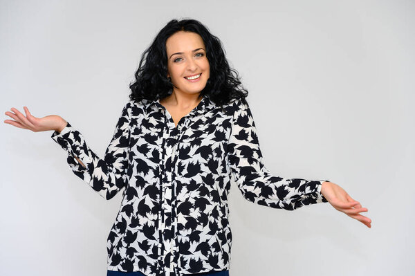 Портрет красивой брюнетки с длинными вьющимися волосами на белом фоне в черно-белой блузке. Он стоит перед камерой, улыбается, говорит в разных позах.
.