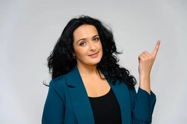 Retrato de una guapa morena con el pelo largo y rizado sobre un fondo blanco en un traje de trabajo. Se para frente a la cámara, sonríe, habla en varias poses . — Foto de Stock