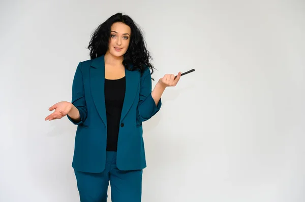 Retrato de una guapa morena con el pelo largo y rizado sobre un fondo blanco en un traje de trabajo. Se para frente a la cámara, sonríe, habla en varias poses . — Foto de Stock