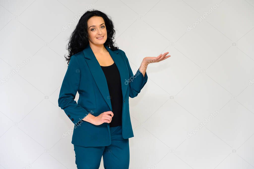 Portrait of a pretty brunette woman with long curly hair on a white background in a business suit. He stands in front of the camera, smiles, talks in various poses.