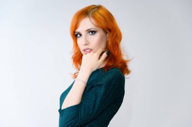 Mükemmel makyajlı, beyaz arka planda parlak kıvırcık saçlı kızıl saçlı güzel bir kızın portresi. Güzellik konsepti, güzel saç stili ve makyaj malzemesi..