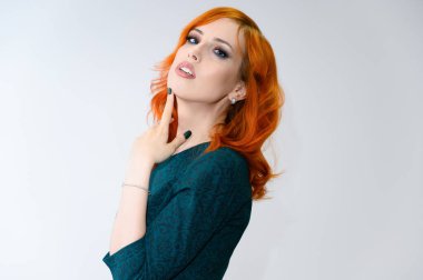 Mükemmel makyajlı, beyaz arka planda parlak kıvırcık saçlı kızıl saçlı güzel bir kızın portresi. Güzellik konsepti, güzel saç stili ve makyaj malzemesi..