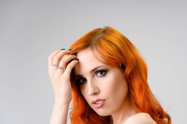 Kızıl saçlı güzel bir kızın yakın plan portresi mükemmel makyajlı ve beyaz arka planda parlak kıvırcık saçlı. Güzellik konsepti, güzel saç stili ve makyaj malzemesi..