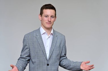 Kameraya konuşan hoş bir genç adam konsepti. Gri bir arka planda, gri takım elbiseli ve çeşitli pozlarda beyaz gömlekli bir sekreterin resmi..