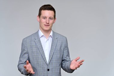 Kameraya konuşan hoş bir genç adam konsepti. Gri bir arka planda, gri takım elbiseli ve çeşitli pozlarda beyaz gömlekli bir sekreterin resmi..