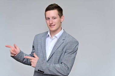 Kameraya konuşan hoş bir genç adam konsepti. Gri bir arka planda, gri takım elbiseli ve çeşitli pozlarda beyaz gömlekli bir sekreterin resmi..
