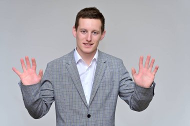 Kameraya konuşan hoş bir genç adam konsepti. Gri bir arka planda, gri takım elbiseli ve çeşitli pozlarda beyaz gömlekli bir sekreterin resmi..