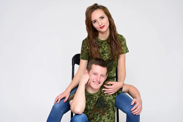 Concepto de relación familiar. Retrato de una agradable familia joven bastante feliz: una chica morena con un hermoso peinado y un tipo en uniforme sobre un fondo blanco . — Foto de Stock