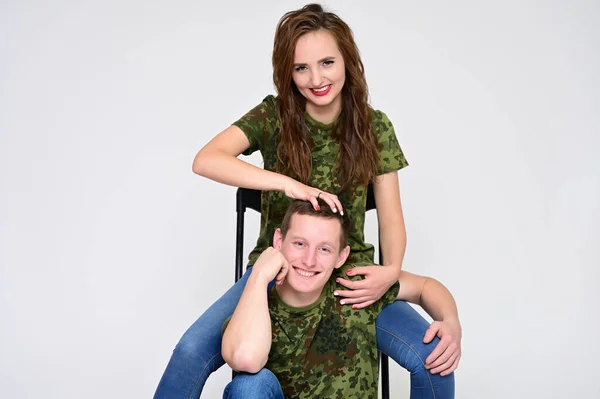 Family Relationship Concept. Portrait of a pleasant young pretty happy family: a brunette girl with a beautiful hairstyle and a guy in uniform on a white background. — Stock Photo, Image