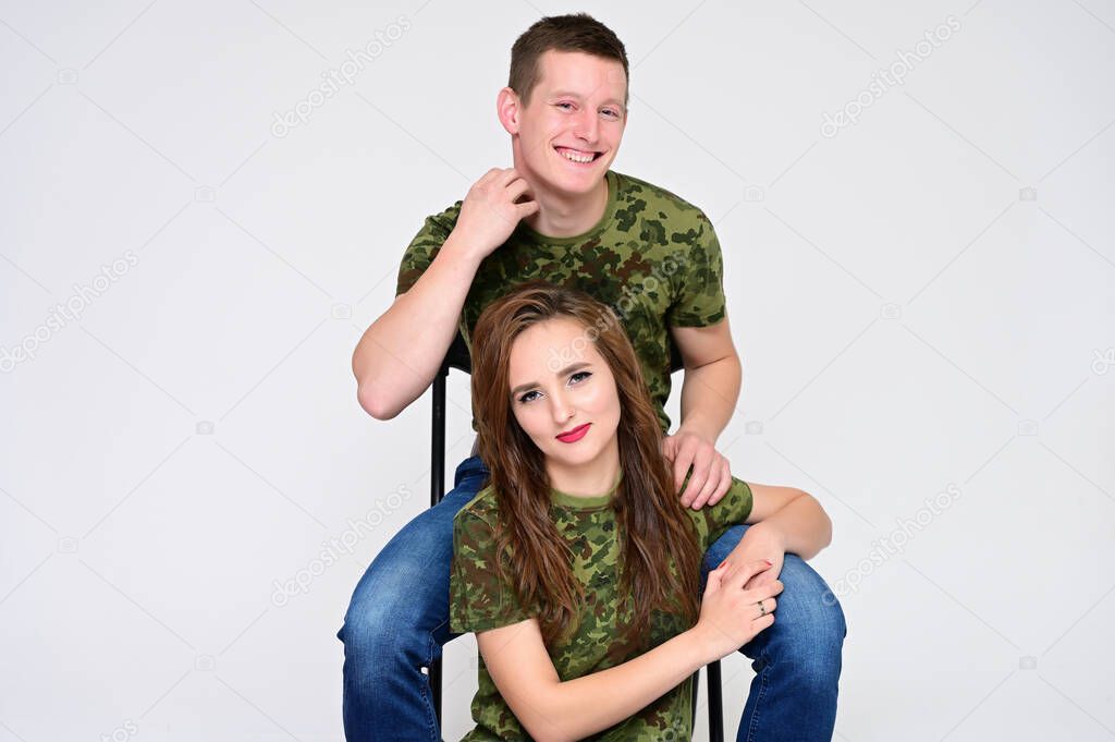 Family Relationship Concept. Portrait of a pleasant young pretty happy family: a brunette girl with a beautiful hairstyle and a guy in uniform on a white background.