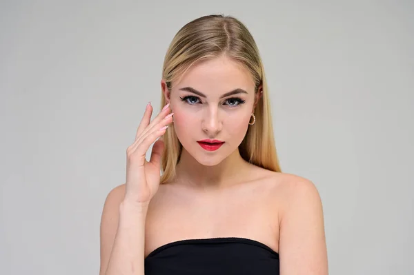 Begreppet kosmetiskt, hud föryngring. Närbild porträtt av en vacker blond modell på en vit bakgrund med långt hår, utmärkt makeup, vackert ansikte och läppar. — Stockfoto