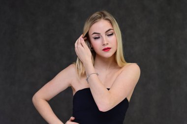 Güzel bir kızla moda cazibe, kozmetik ve güzellik kavramı. Gri bir arka planda, uzun saçlı, harika makyajlı zarif sarışın bir mankenin portresi..