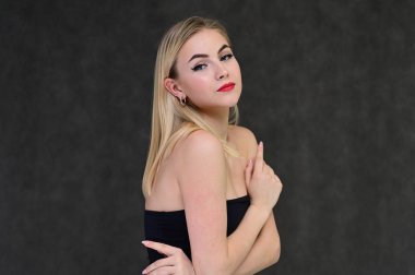 Güzel bir kızla moda cazibe, kozmetik ve güzellik kavramı. Gri bir arka planda, uzun saçlı, harika makyajlı zarif sarışın bir mankenin portresi..