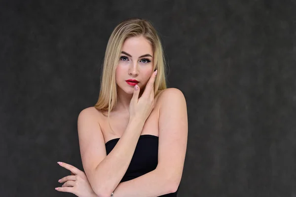 El concepto de glamour de moda, cosméticos y belleza con una chica bonita. Retrato de una modelo rubia hermosa de moda con el pelo largo, gran maquillaje, sobre un fondo gris . — Foto de Stock