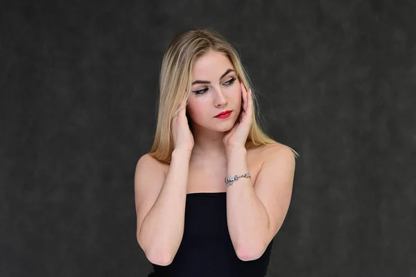 The concept of fashionable glamor, cosmetics and beauty with a pretty girl. Portrait of a fashionable beautiful blonde model with long hair, great makeup, on a gray background. — ストック写真