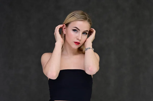 Begreppet modern glamour, kosmetika och skönhet med en söt flicka. Porträtt av en fashionabel vacker blond modell med långt hår, bra makeup, på en grå bakgrund. — Stockfoto