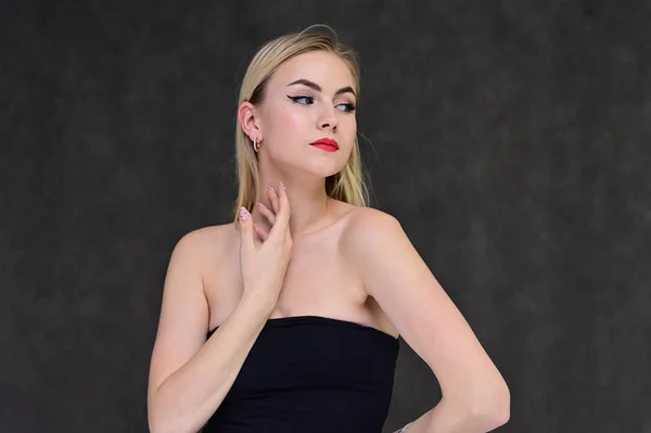 Das Konzept der modischen Glamour, Kosmetik und Schönheit mit einem hübschen Mädchen. Porträt einer modischen schönen blonden Model mit langen Haaren, tolles Make-up, auf einem grauen Hintergrund. — Stockfoto