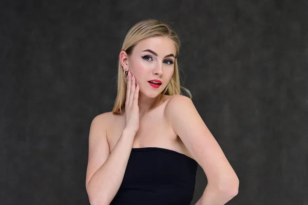 The concept of fashionable glamor, cosmetics and beauty with a pretty girl. Portrait of a fashionable beautiful blonde model with long hair, great makeup, on a gray background. — ストック写真