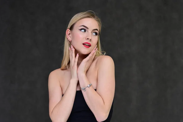 Begreppet modern glamour, kosmetika och skönhet med en söt flicka. Porträtt av en fashionabel vacker blond modell med långt hår, bra makeup, på en grå bakgrund. — Stockfoto