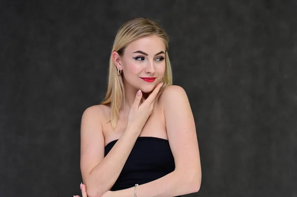 Das Konzept der modischen Glamour, Kosmetik und Schönheit mit einem hübschen Mädchen. Porträt einer modischen schönen blonden Model mit langen Haaren, tolles Make-up, auf einem grauen Hintergrund. — Stockfoto