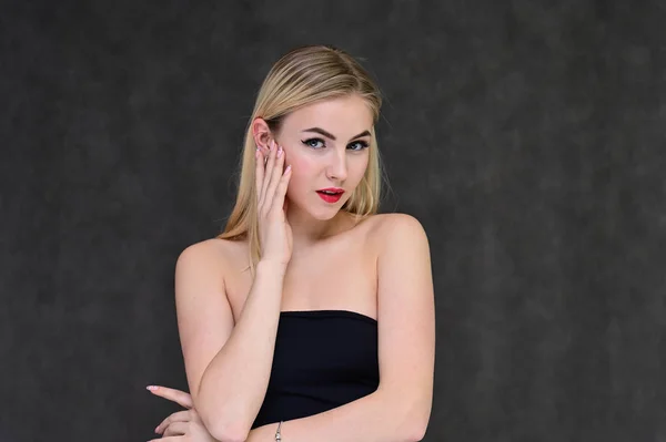 Begreppet modern glamour, kosmetika och skönhet med en söt flicka. Porträtt av en fashionabel vacker blond modell med långt hår, bra makeup, på en grå bakgrund. — Stockfoto