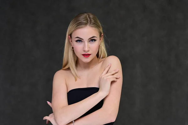 Das Konzept der modischen Glamour, Kosmetik und Schönheit mit einem hübschen Mädchen. Porträt einer modischen schönen blonden Model mit langen Haaren, tolles Make-up, auf einem grauen Hintergrund. — Stockfoto