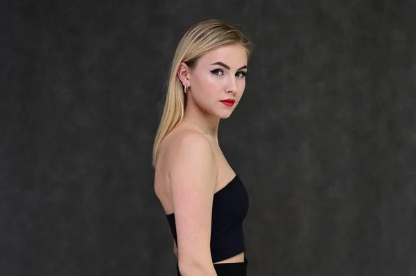 Begreppet modern glamour, kosmetika och skönhet med en söt flicka. Porträtt av en fashionabel vacker blond modell med långt hår, bra makeup, på en grå bakgrund. — Stockfoto