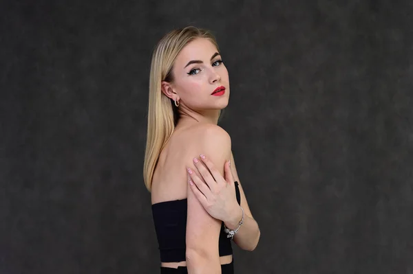 Begreppet modern glamour, kosmetika och skönhet med en söt flicka. Porträtt av en fashionabel vacker blond modell med långt hår, bra makeup, på en grå bakgrund. — Stockfoto