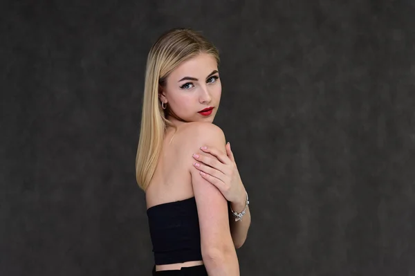 Begreppet modern glamour, kosmetika och skönhet med en söt flicka. Porträtt av en fashionabel vacker blond modell med långt hår, bra makeup, på en grå bakgrund. — Stockfoto