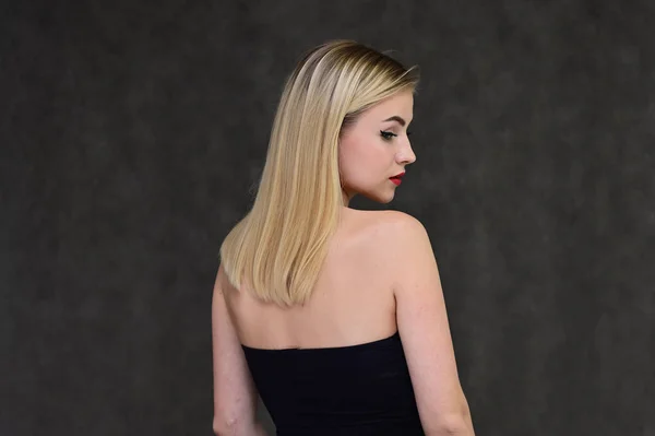 Het concept van modieuze glamour, cosmetica en schoonheid met een mooi meisje. Portret van een modieus mooi blond model met lang haar, geweldige make-up, op een grijze achtergrond. — Stockfoto