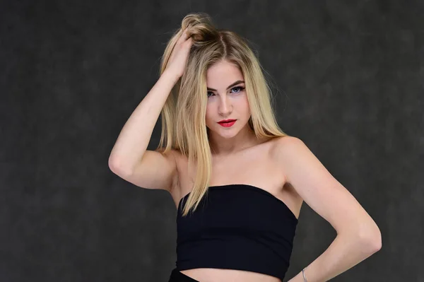 Begreppet modern glamour, kosmetika och skönhet med en söt flicka. Porträtt av en fashionabel vacker blond modell med långt hår, bra makeup, på en grå bakgrund. — Stockfoto