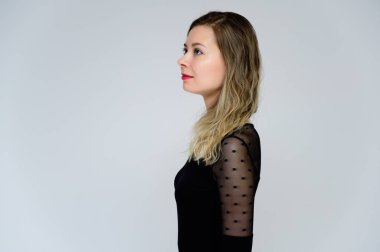 Bir kadının kameranın önünde konuşması fikri. Beyaz arka planda siyah tişörtlü, gülümseyen güzel bir kızın profil fotoğrafı kameranın önünde duruyor..