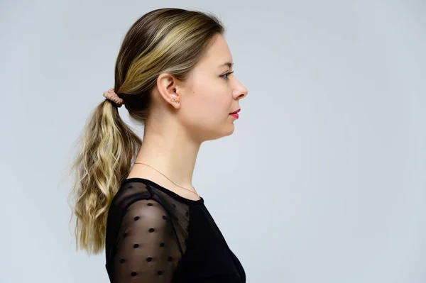 Conceito de uma mulher de perfil em frente à câmara. Foto de perfil de uma menina muito sorridente com cabelo encaracolado em uma camiseta preta em um fundo branco . — Fotografia de Stock